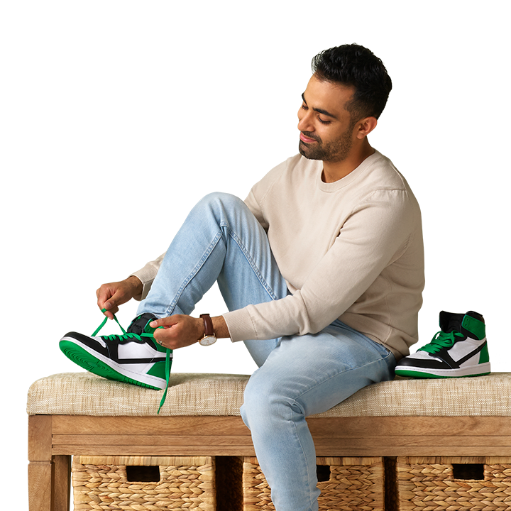 young south asian male putting on his white and green sneakers
